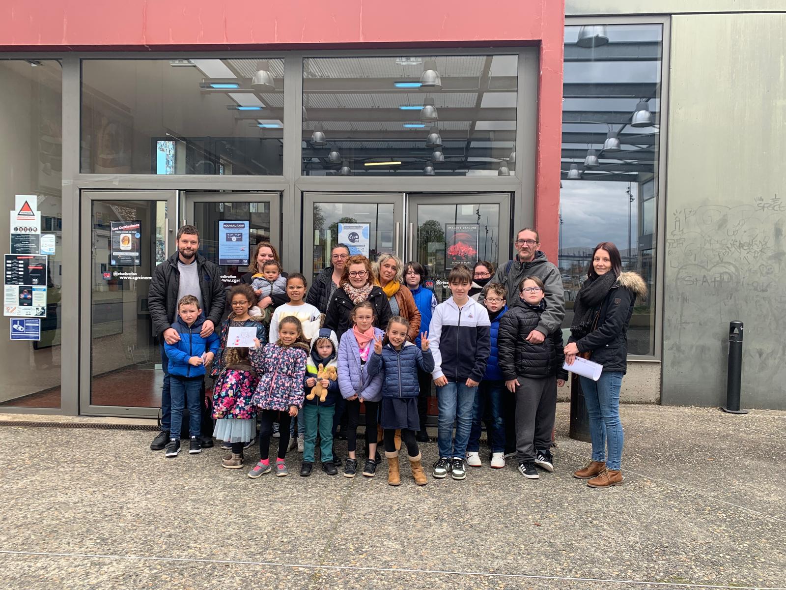 Groupe des plusieurs familles avec leurs enfance devant un cinéma