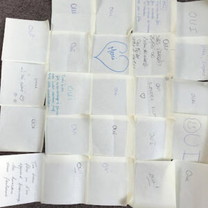 Post-it blancs avec des messages de soutien à un projet parental, rassemblés en un carré sur un tapis.